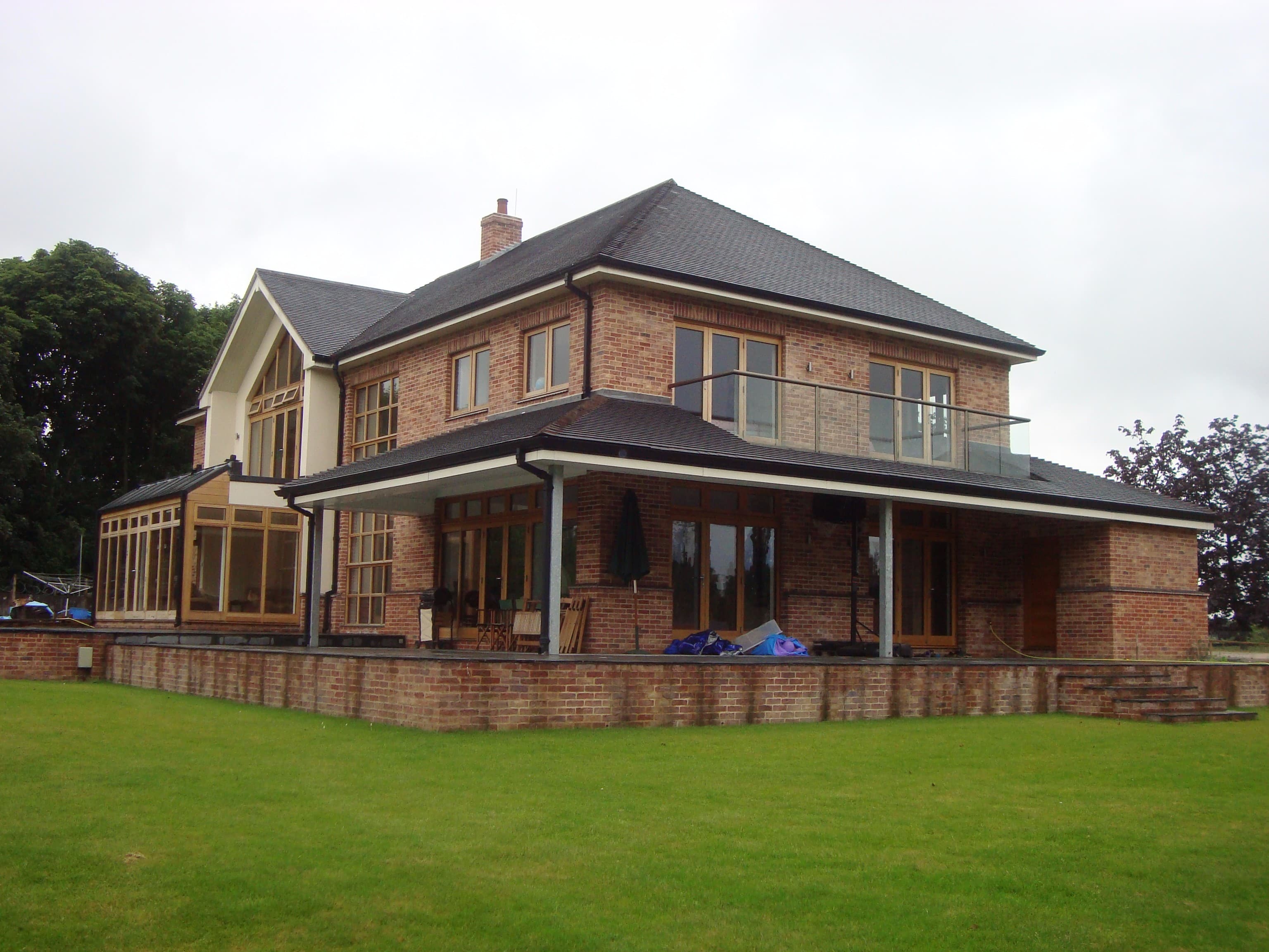 Rear elevation of a two-storey brick new-build with a glazed balcony